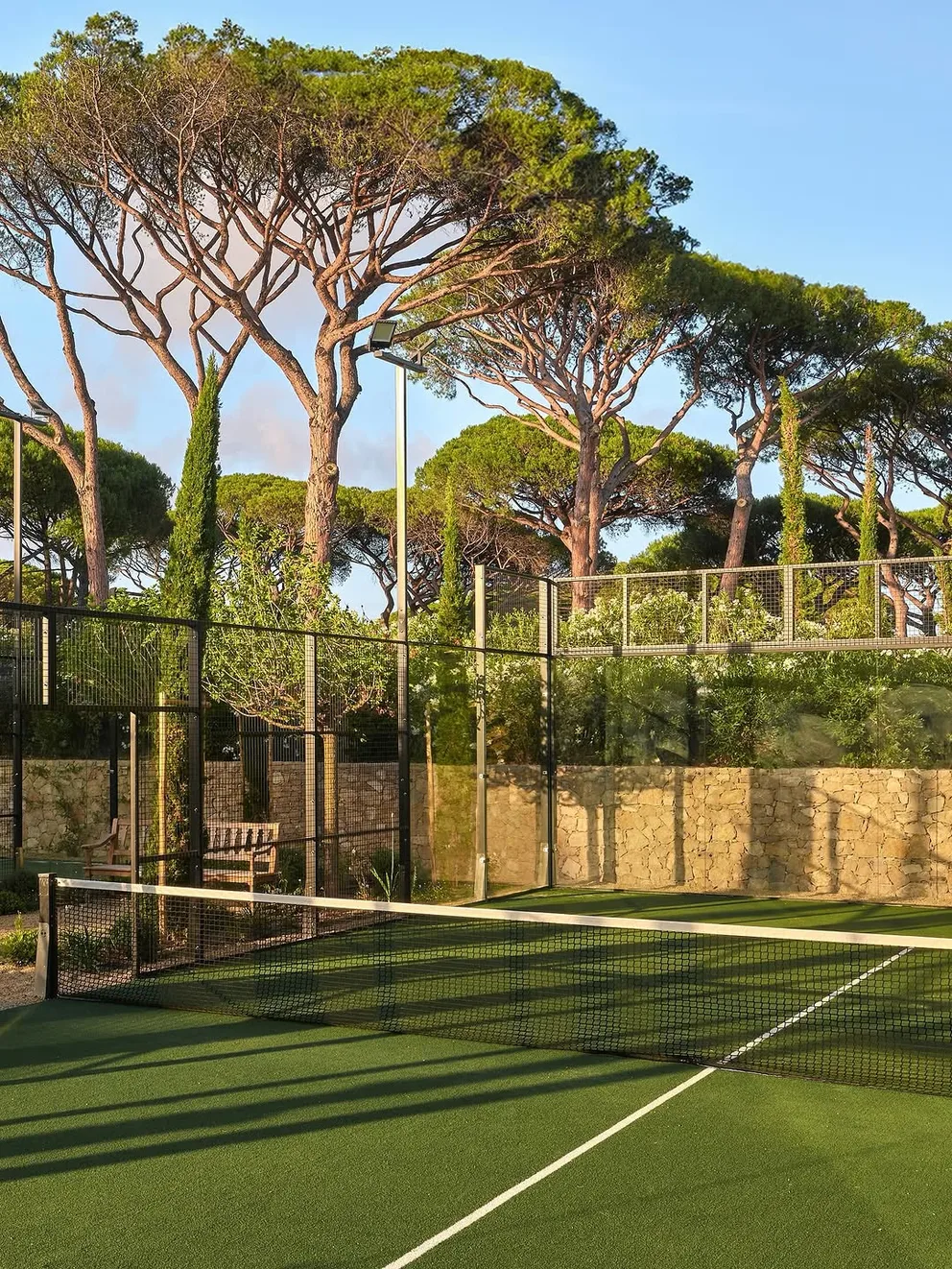 A court set into the gardens among pines and stone walls at Château de la Messardière