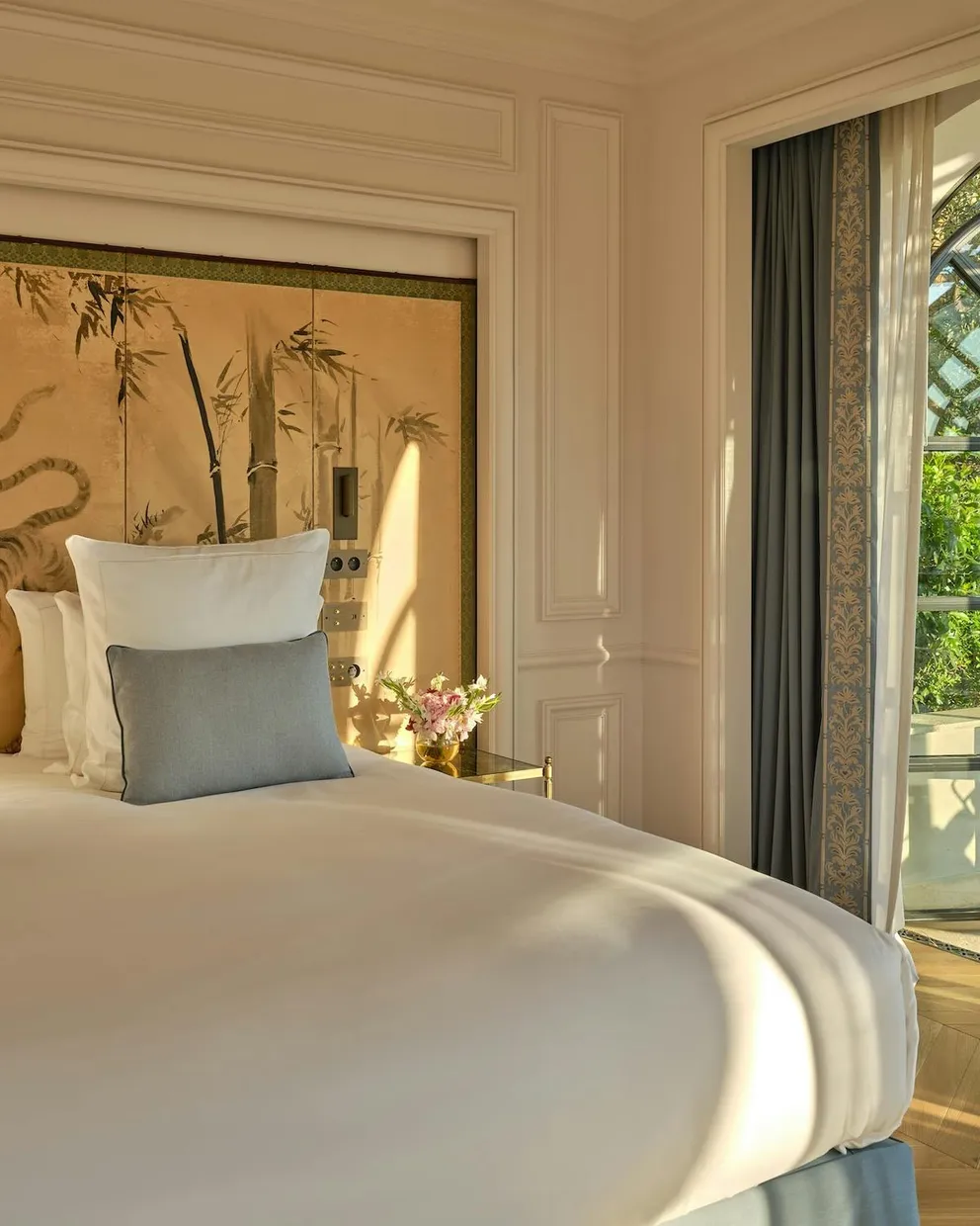 A bedroom at Château de la Messardière with a gilded bamboo screen above the bed