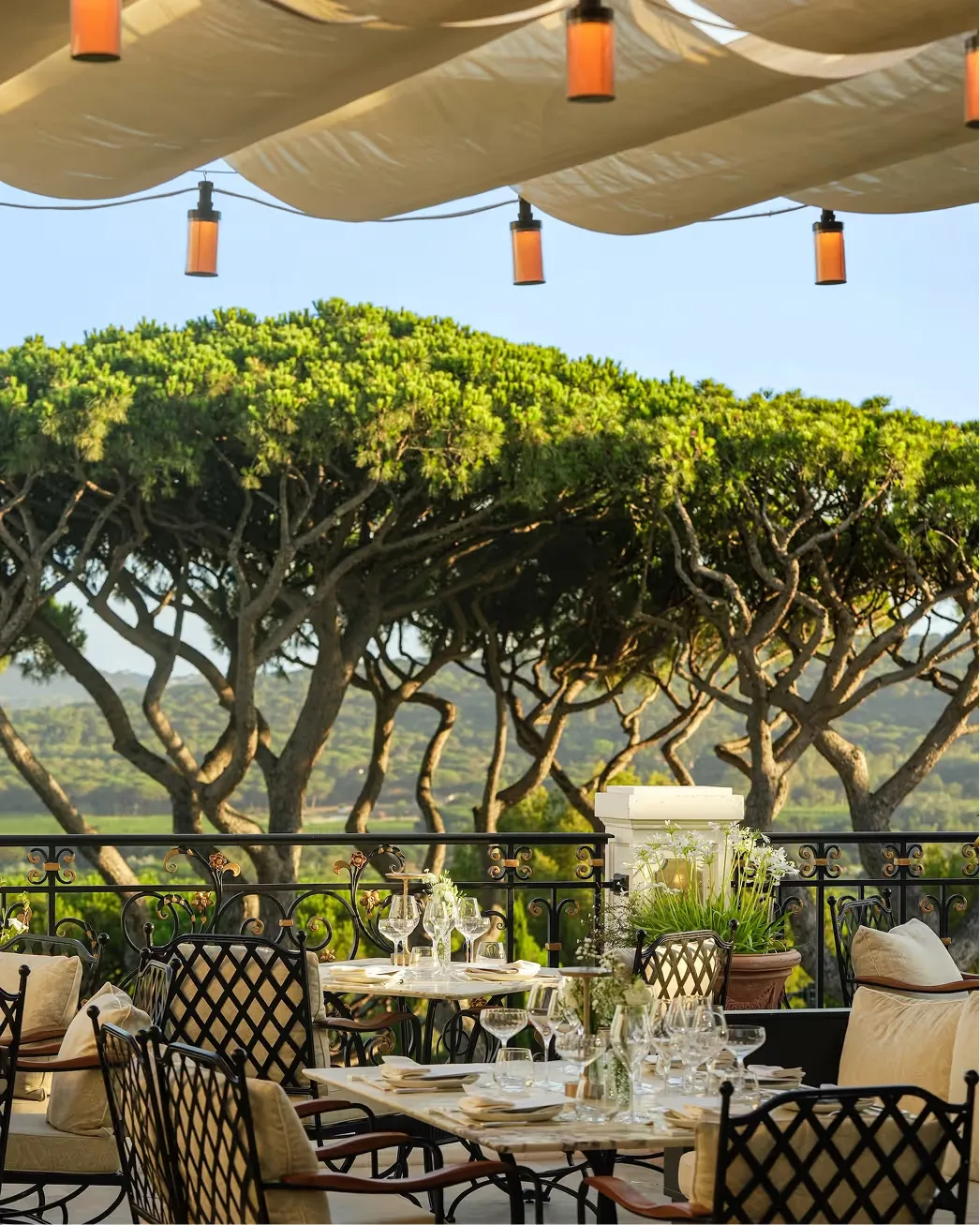 Terraced dining area with orange lanterns and draped shade above Mediterranean views