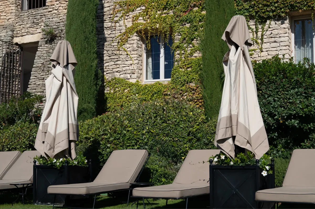 Stone terrace with closed umbrellas and lounge chairs beside stone walls