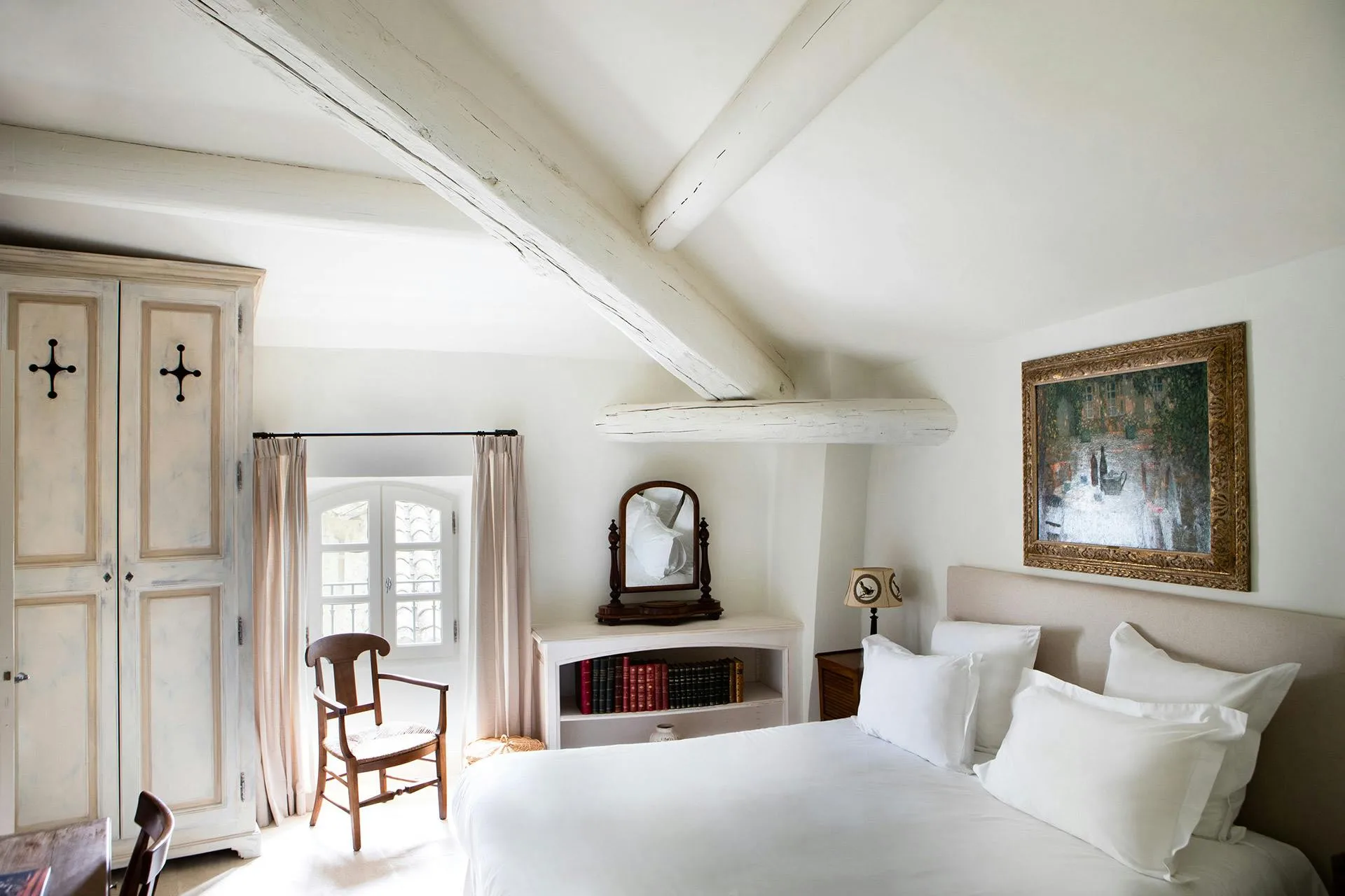 Bedroom under sloped ceiling with exposed beams and fireplace