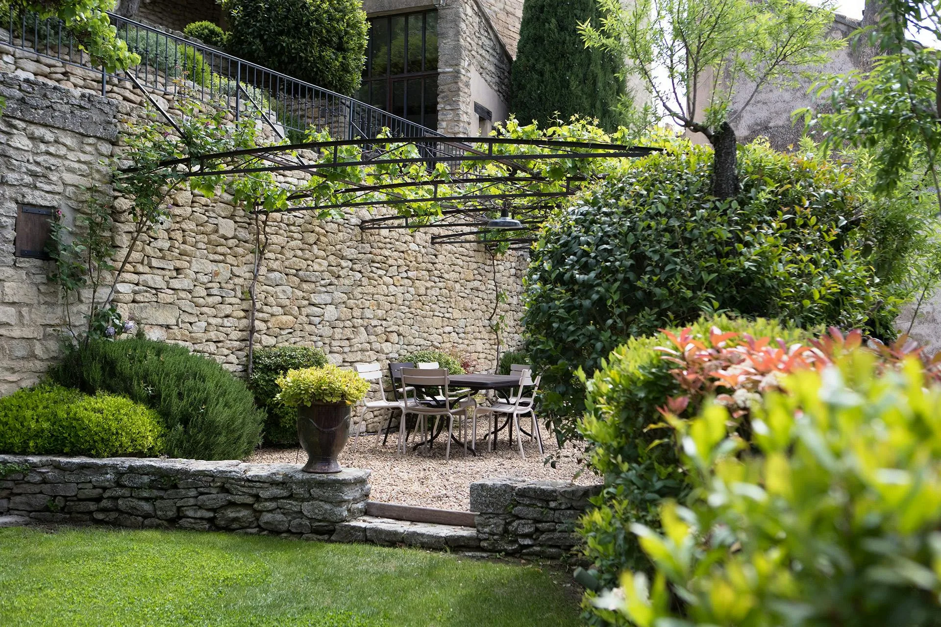 Garden terrace with stone walls, flowering plants, and metal furniture