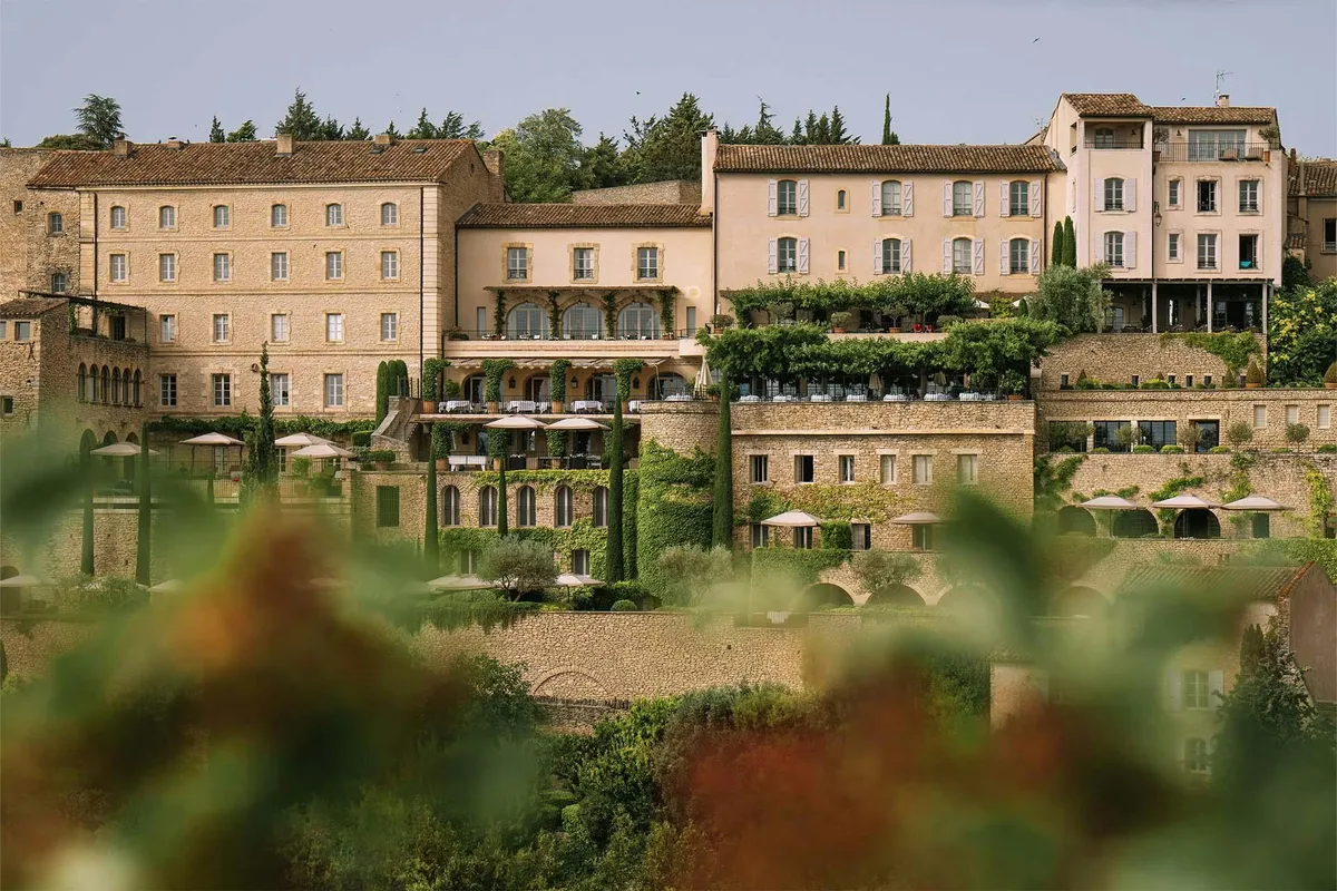 The honey stone facade of the hotel rising from terraced gardens