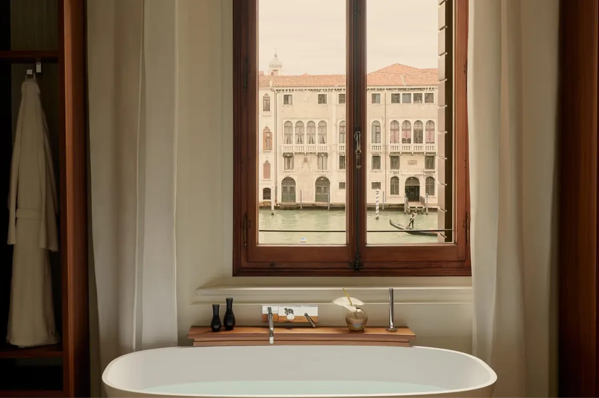 A soaking tub positioned at a tall window overlooking the Grand Canal with wooden trim framing the view