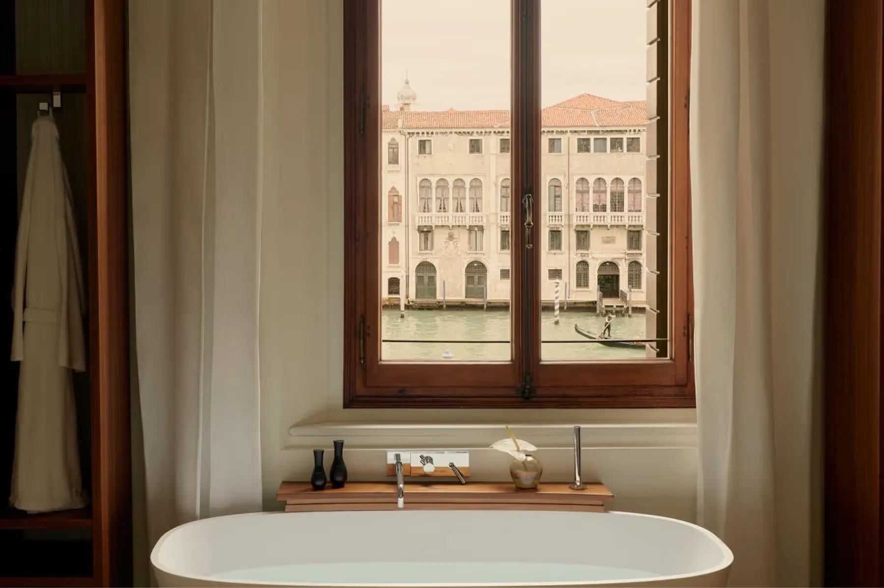A soaking tub positioned at a tall window overlooking the Grand Canal with wooden trim framing the view