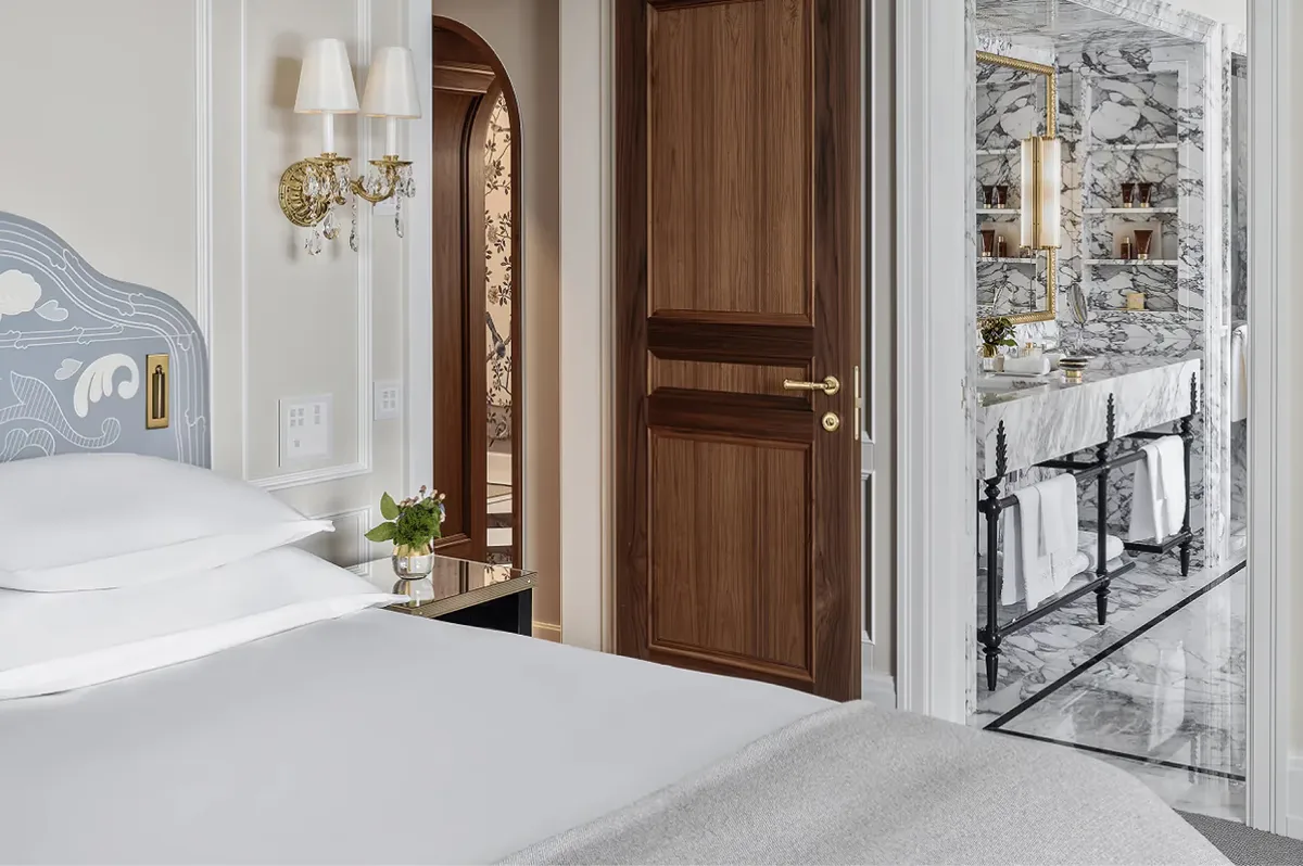Hallway with white walls, wooden doors, and light stone flooring