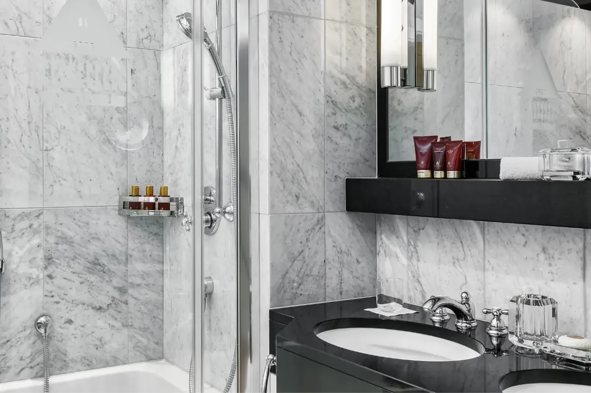 Bathroom with marble shower enclosure, black vanity, and brass accessories