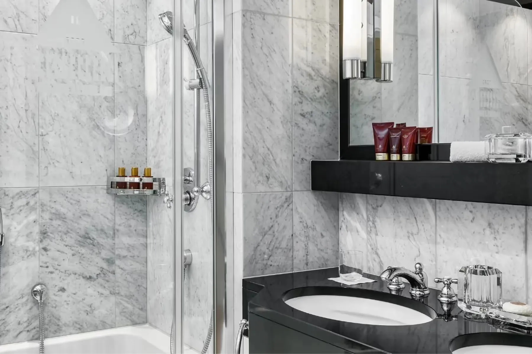 Bathroom with marble shower enclosure, black vanity, and brass accessories
