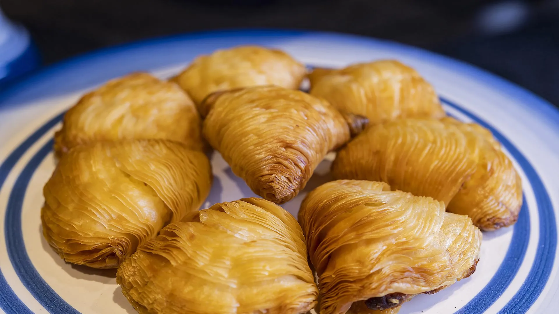 Golden pastries on a ceramic plate with blue-and-white trim, traditional Italian desserts