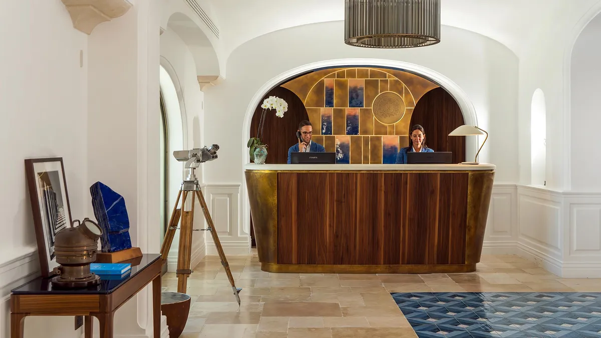 Reception desk in curved stone alcove with wooden cabinetry in whitewashed interior