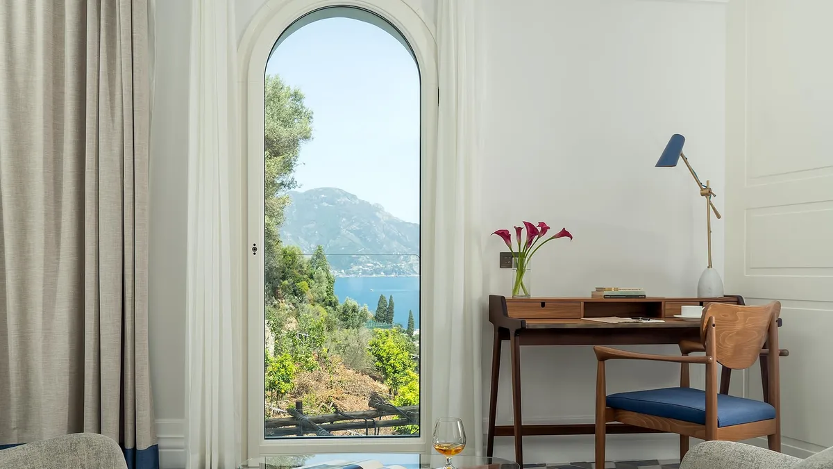 Suite with arched opening framing mountain and sea views, midcentury furnishings