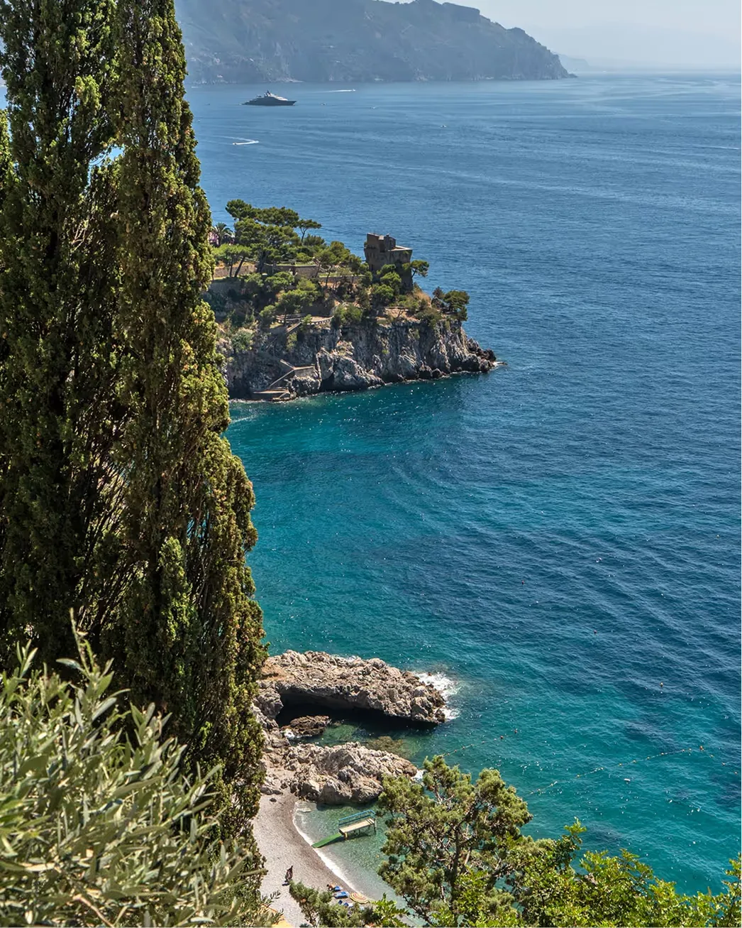 Clifftop gardens with sea views, boats anchored in turquoise waters below