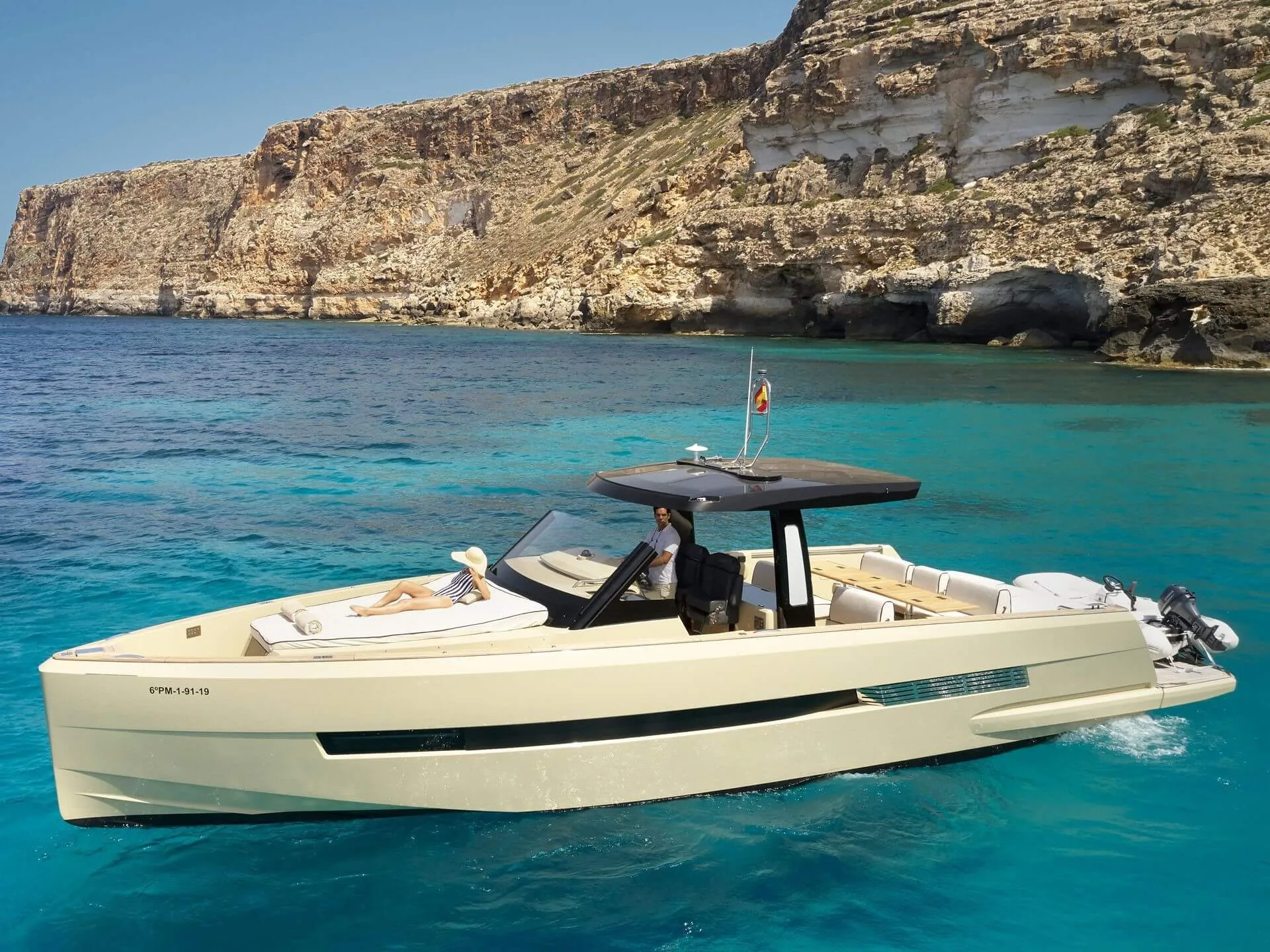 A motorboat in crystal turquoise waters framed by limestone cliffs at Cala Blava