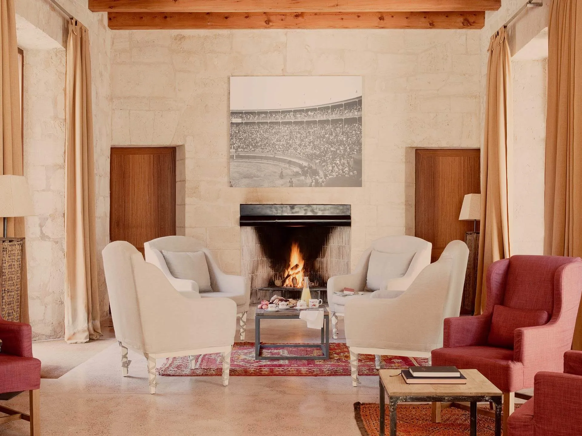 A living room with cream chairs, fireplace, warm wood paneling, and traditional architecture