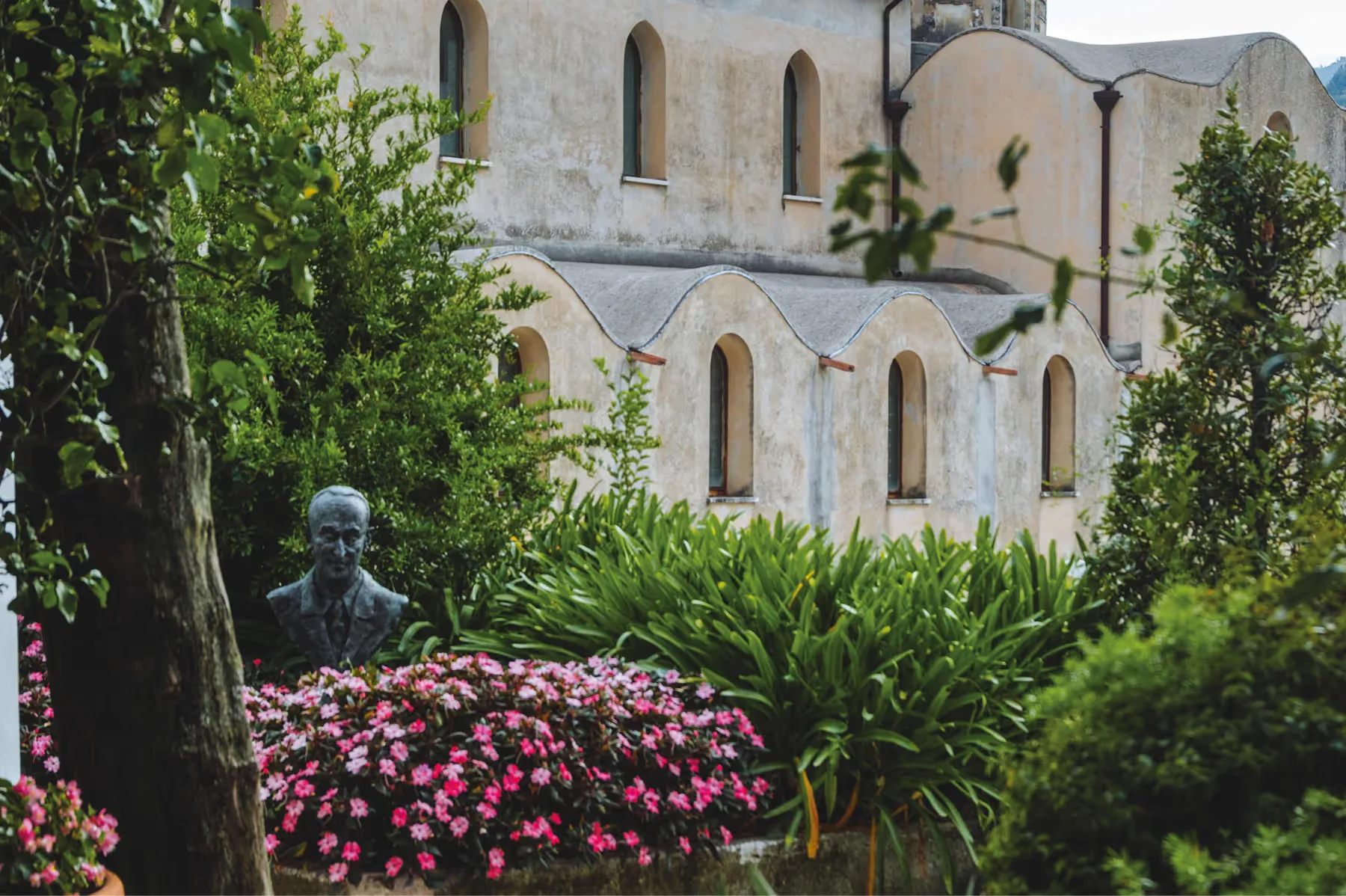 Mediterranean palace exterior with flowering magenta plants and stone balcony overlooking coast