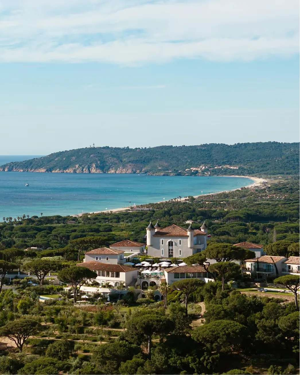 Vertical view of the château tower and surrounding gardens set amid green hills and coastline