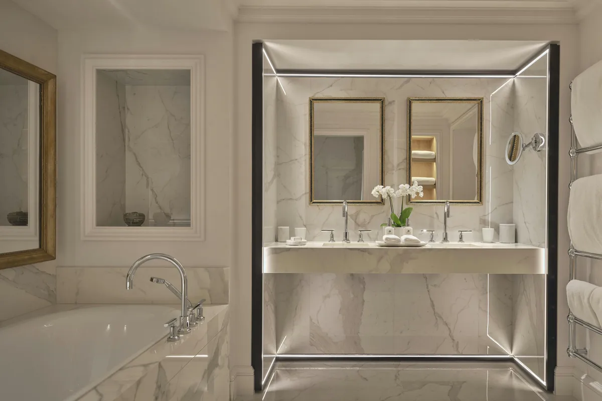 Marble bathroom with gold fixtures and a mirrored vanity cabinet