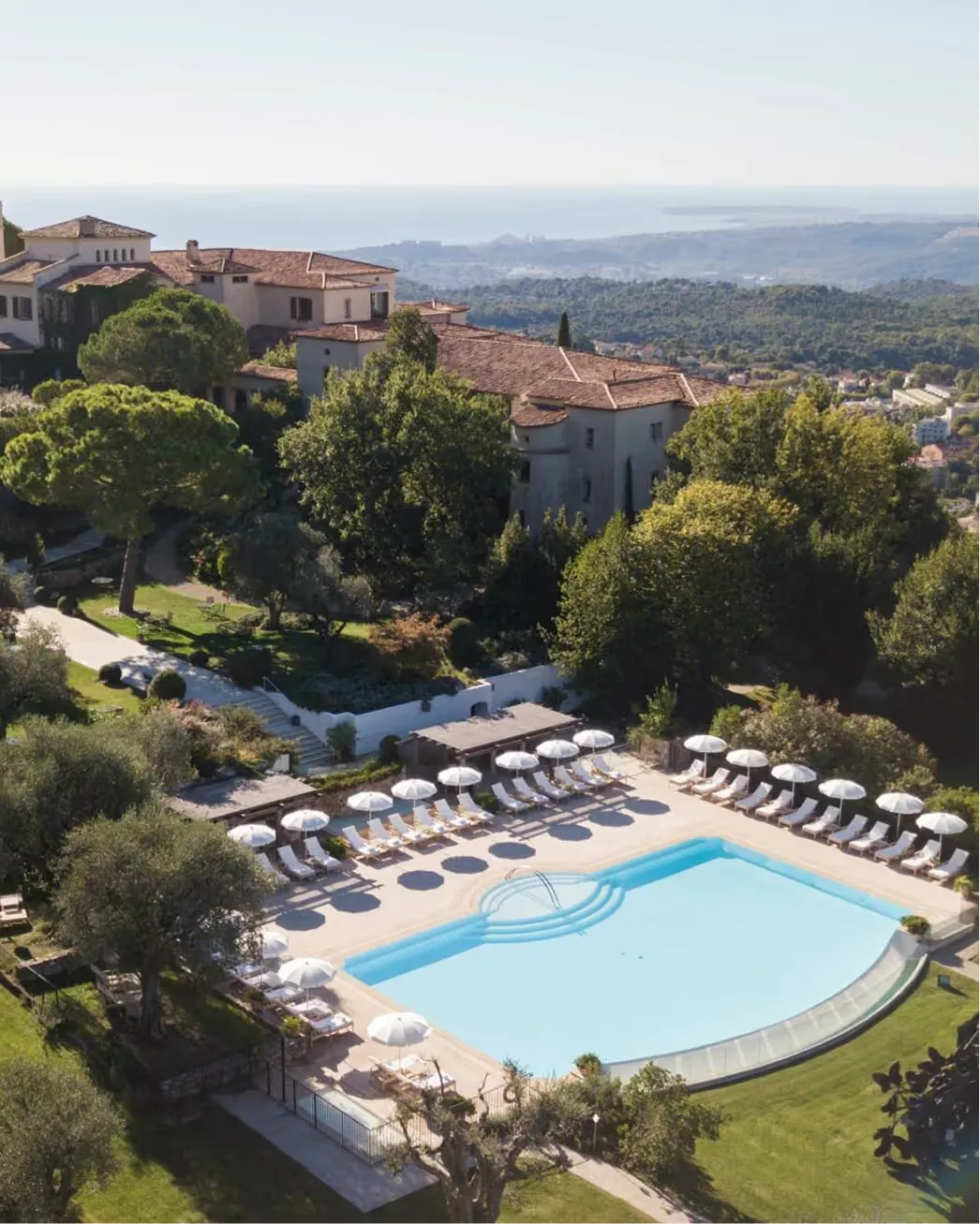 Château with heated infinity pool and lounge chairs overlooking Mediterranean hills