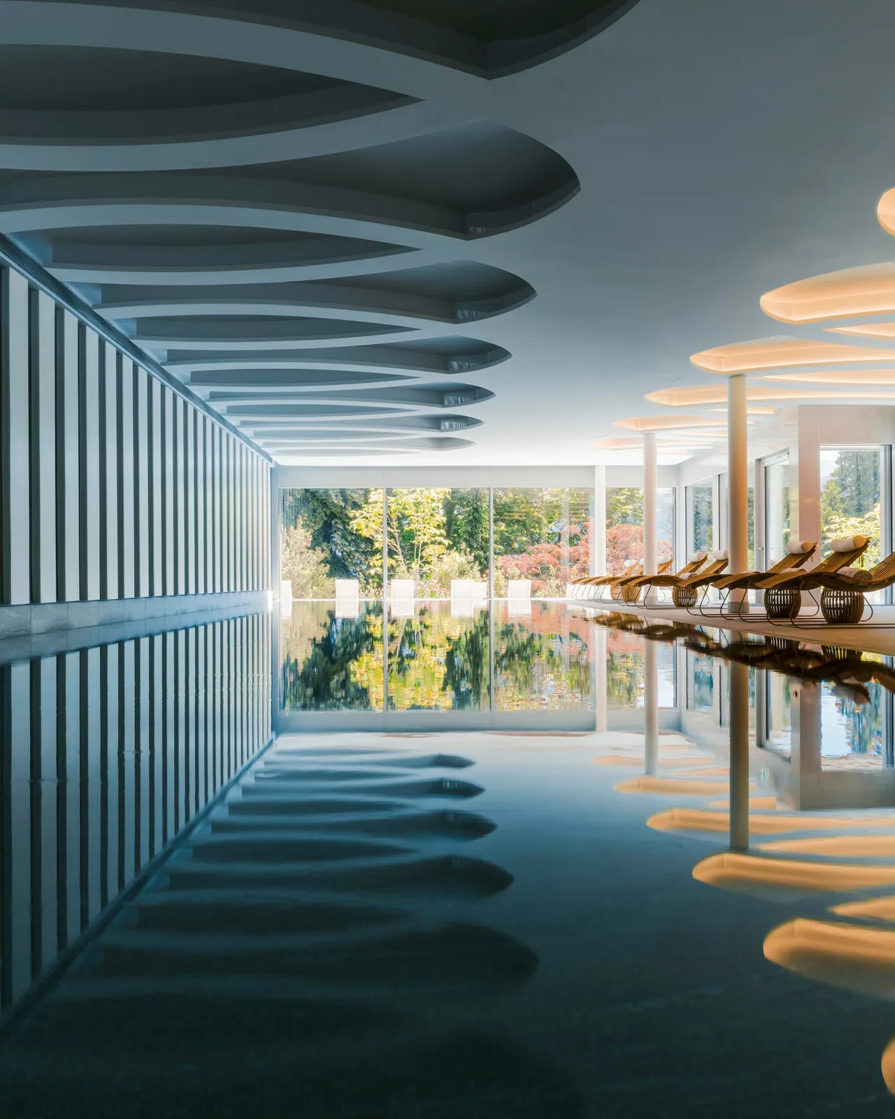 Vertical view of a spa corridor with reflective floor and lake-facing windows under striped ceiling