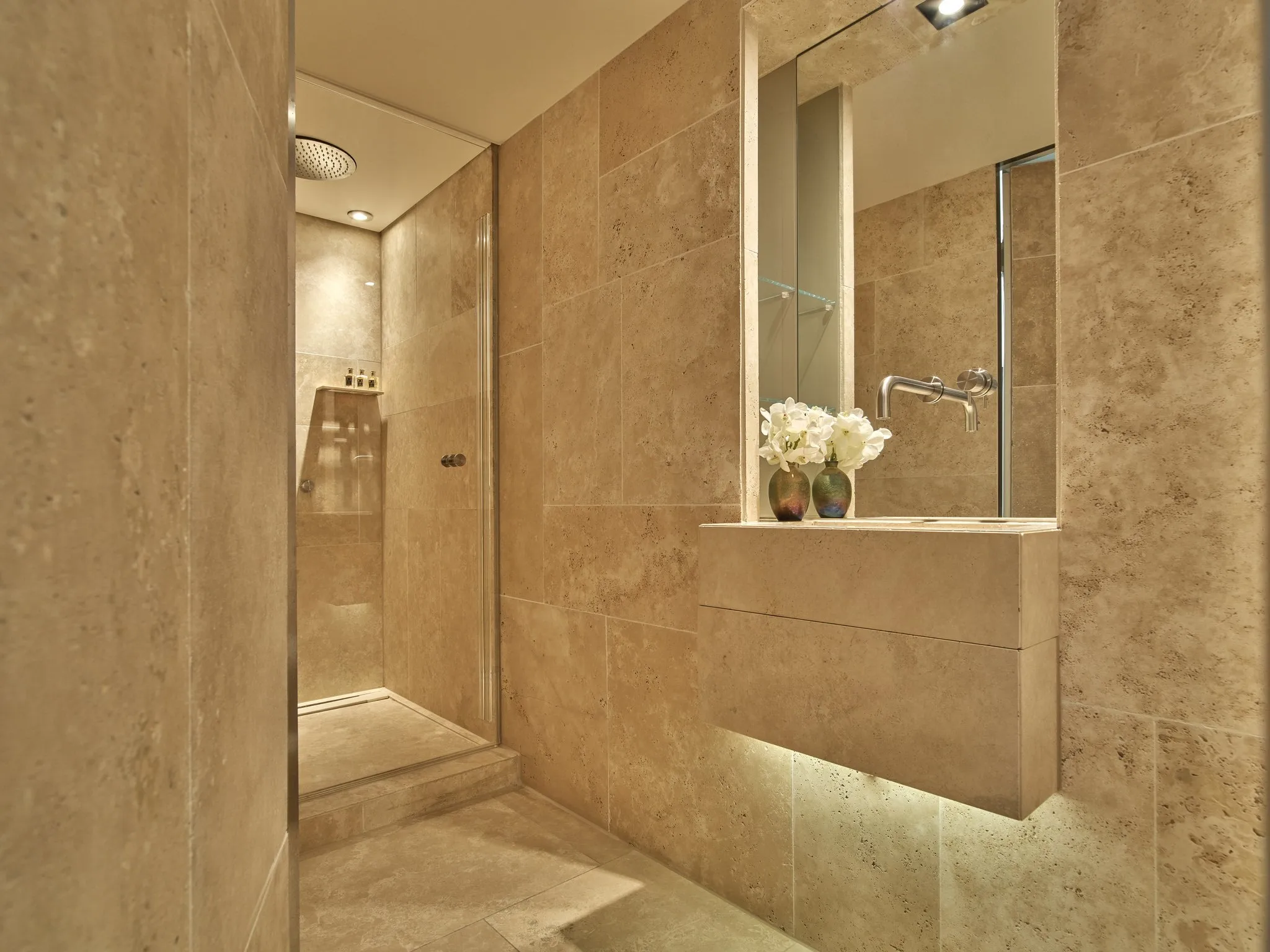 Modern marble spa bathroom with walk-in shower, built-in wall niche, and soft lighting