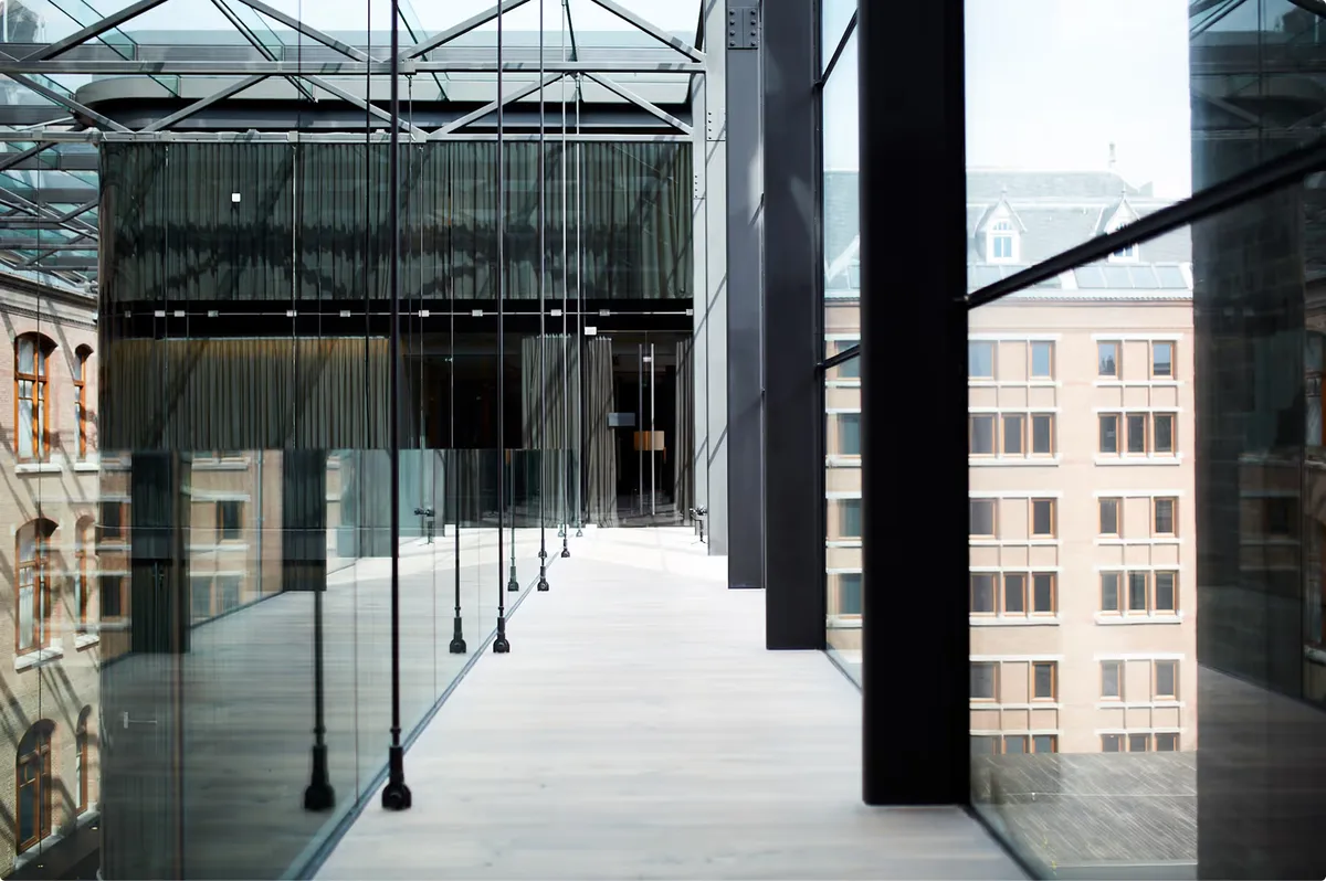 Modern rooftop terrace with floor-to-ceiling glass panels, dark columns, and city views