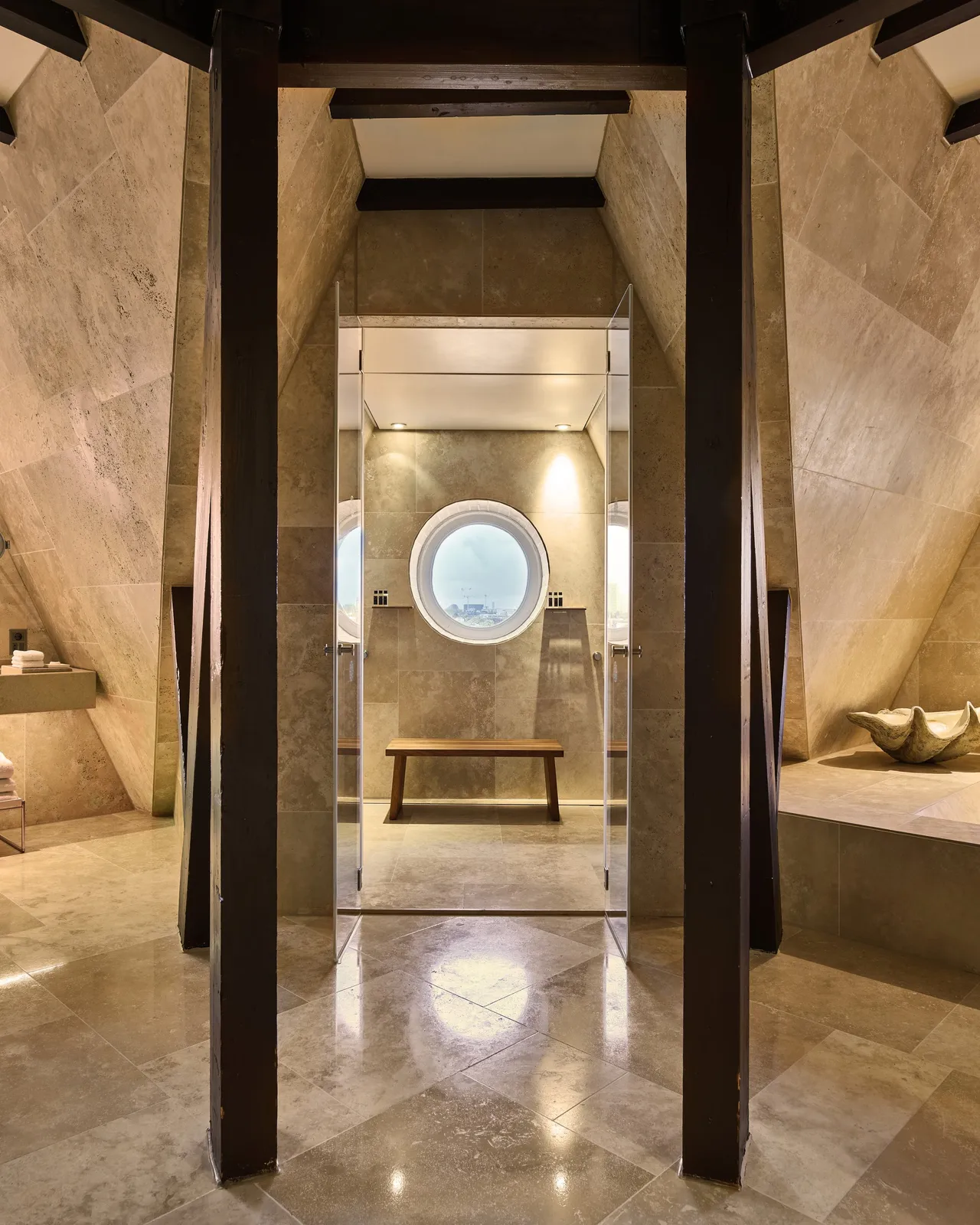 Spa corridor with travertine stone, centered oval window, and polished floors