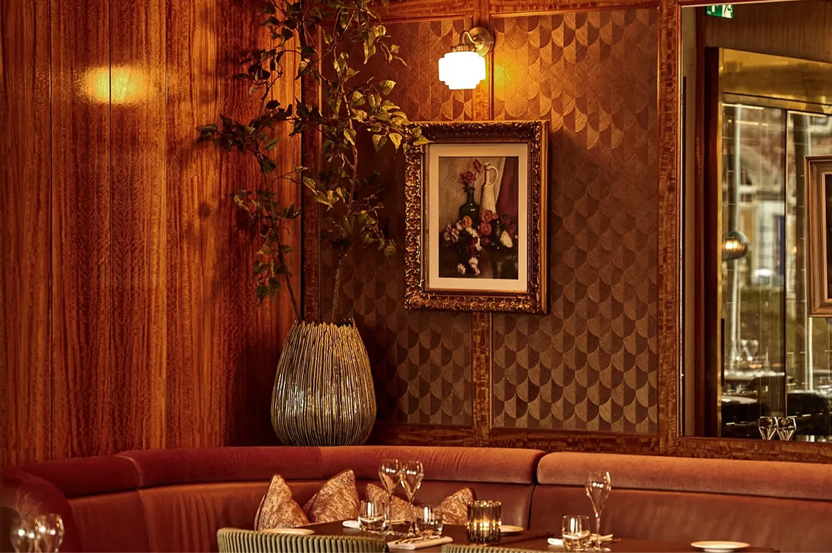 Intimate bar area with mirrored walls, warm wood paneling, and ornamental details