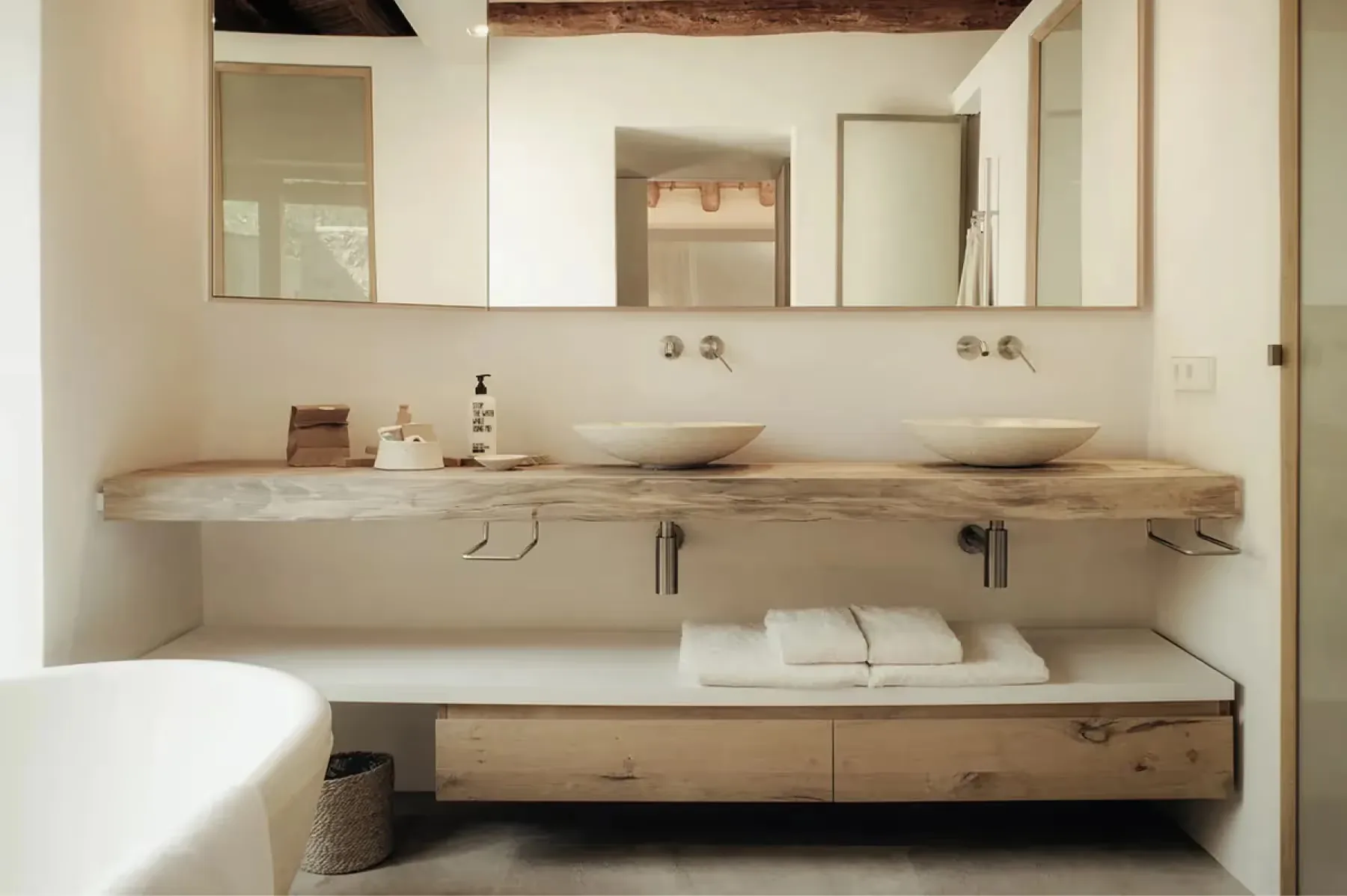 Minimalist bathroom with live-edge wood countertop, paired mirrors, and recessed lighting above sink