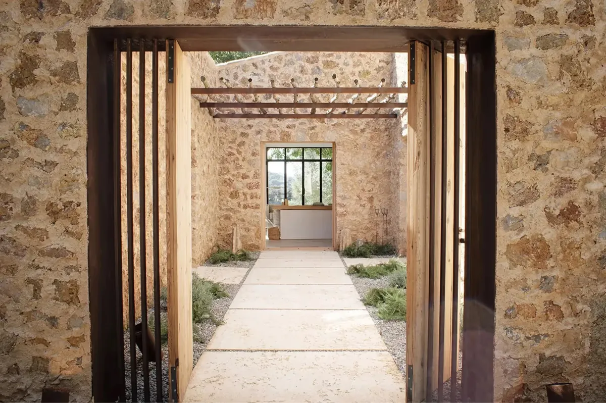 Passageway through stone walls with wooden doors and natural light spilling across floor