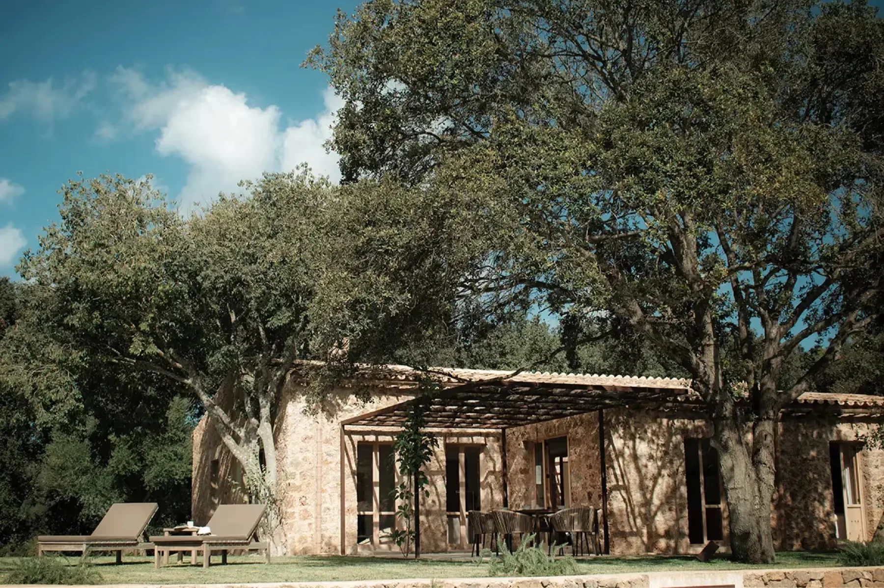 Traditional stone casita building set in wooded valley landscape with bright Mediterranean light
