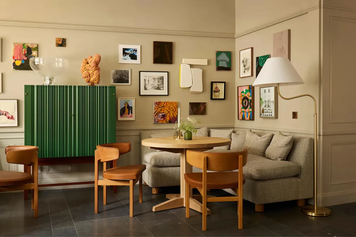 A lounge with green accent wall, wooden furniture, and wall-mounted artwork collection