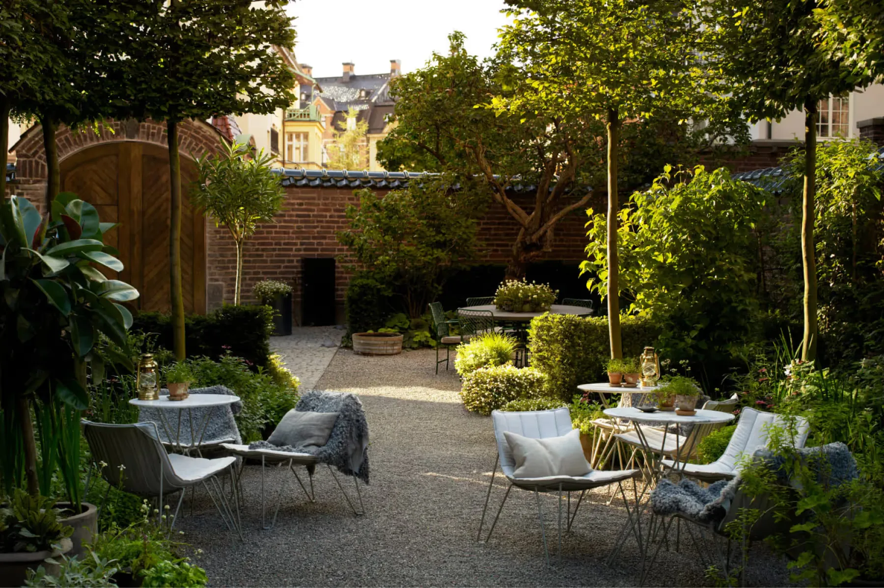 An outdoor garden seating area with white lounge chairs under trees