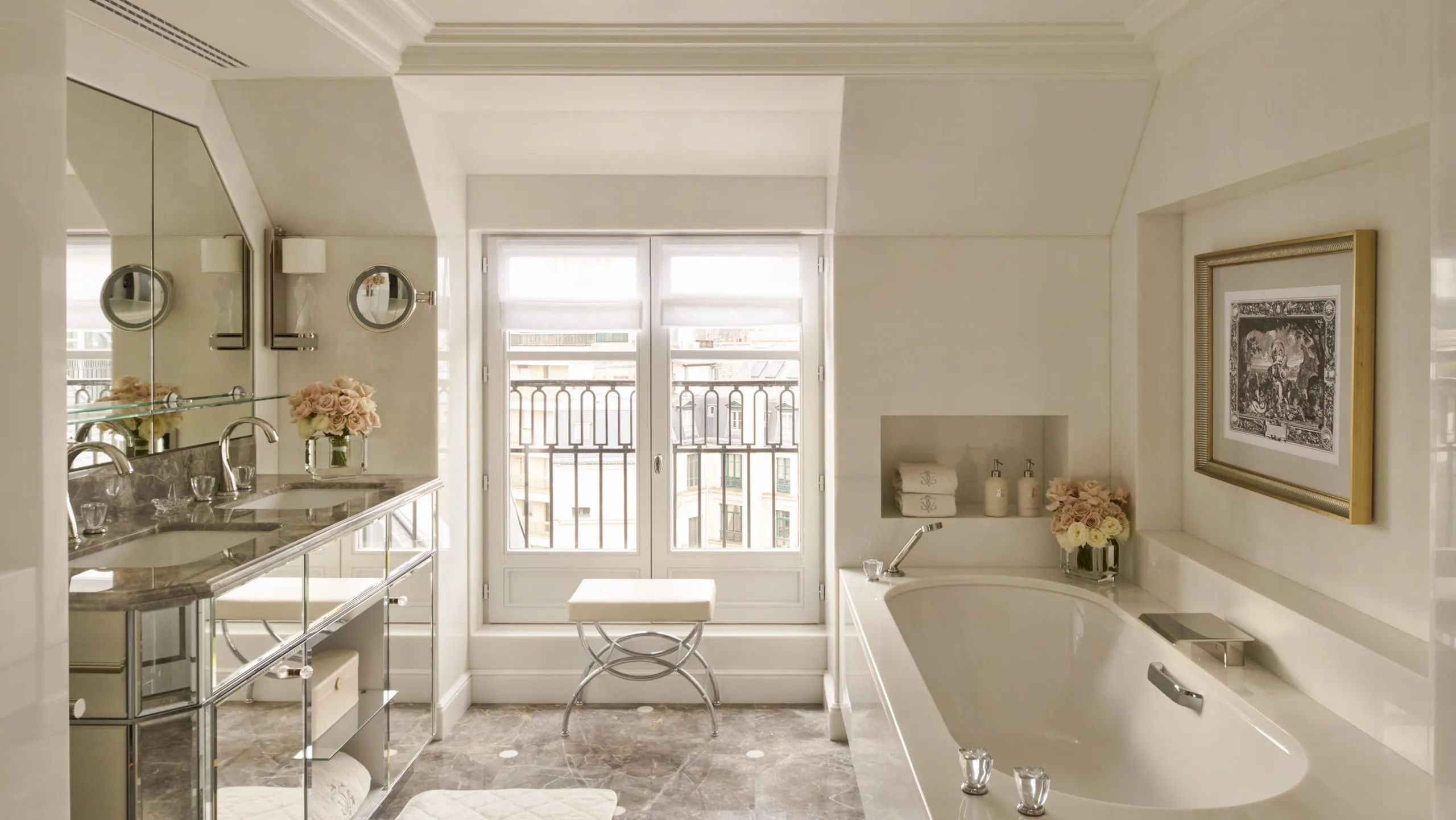 A marble bathroom with vanity, curved windows framing the city view, and a soaking tub