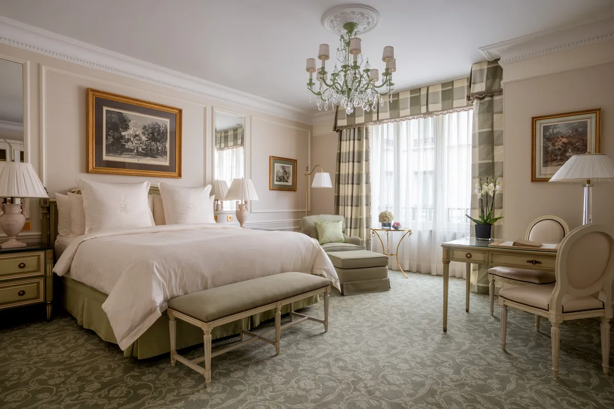 A classical bedroom with gilt accents, arched ceiling details, and a chandelier