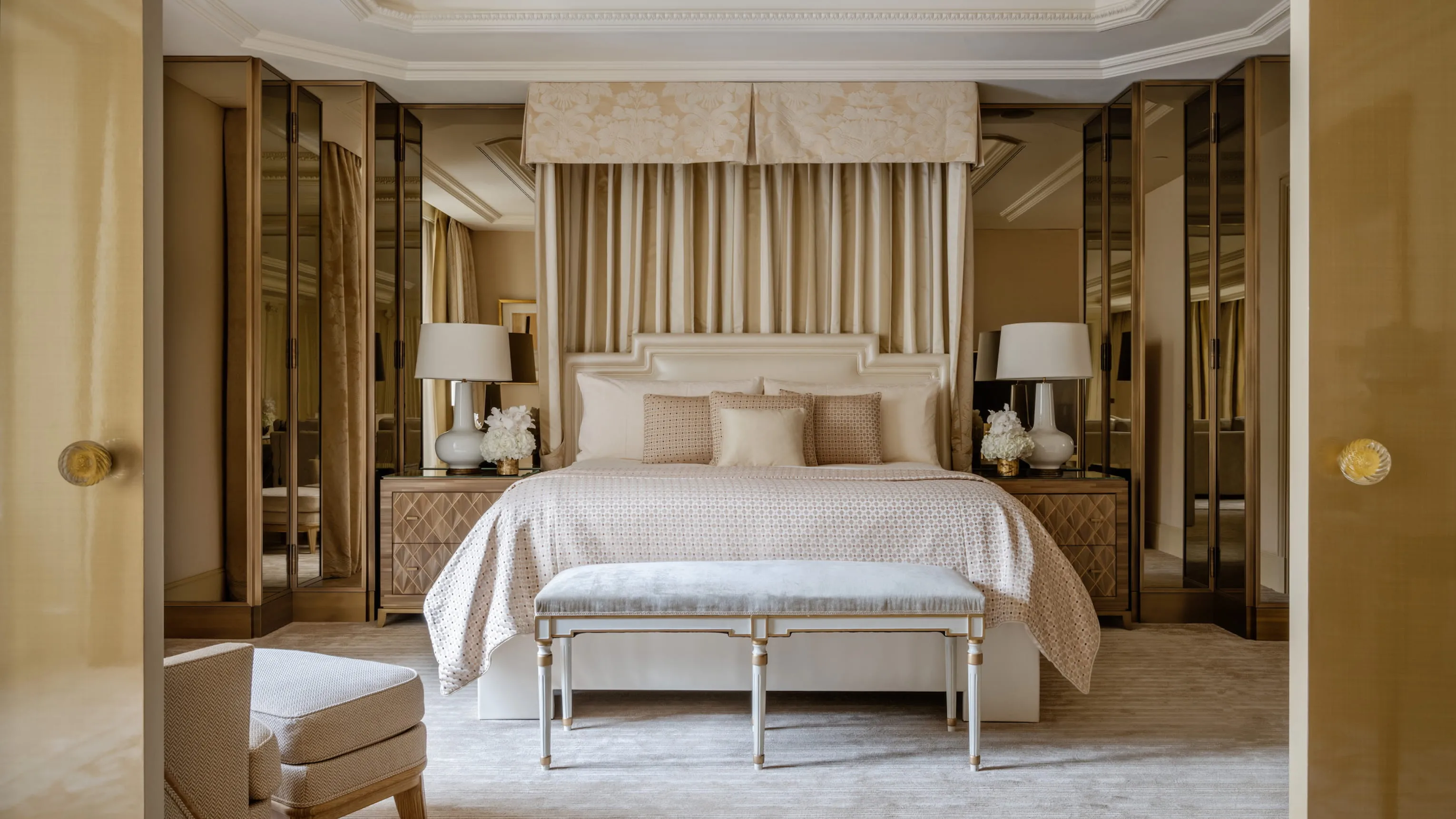 A spacious bedroom with a bed framed by wood wall panels and dress cabinets