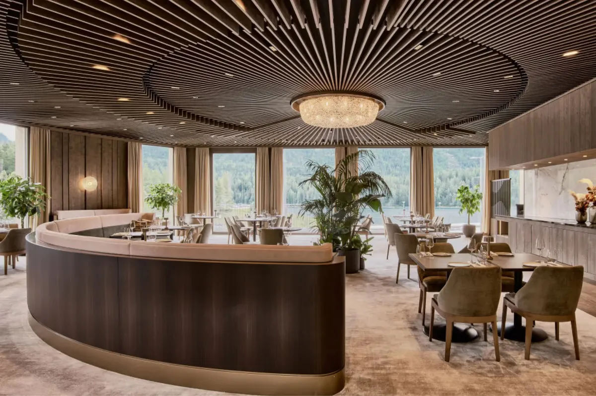 Modern dining space with curved dark wood bar, pendant lighting, and floor-to-ceiling windows