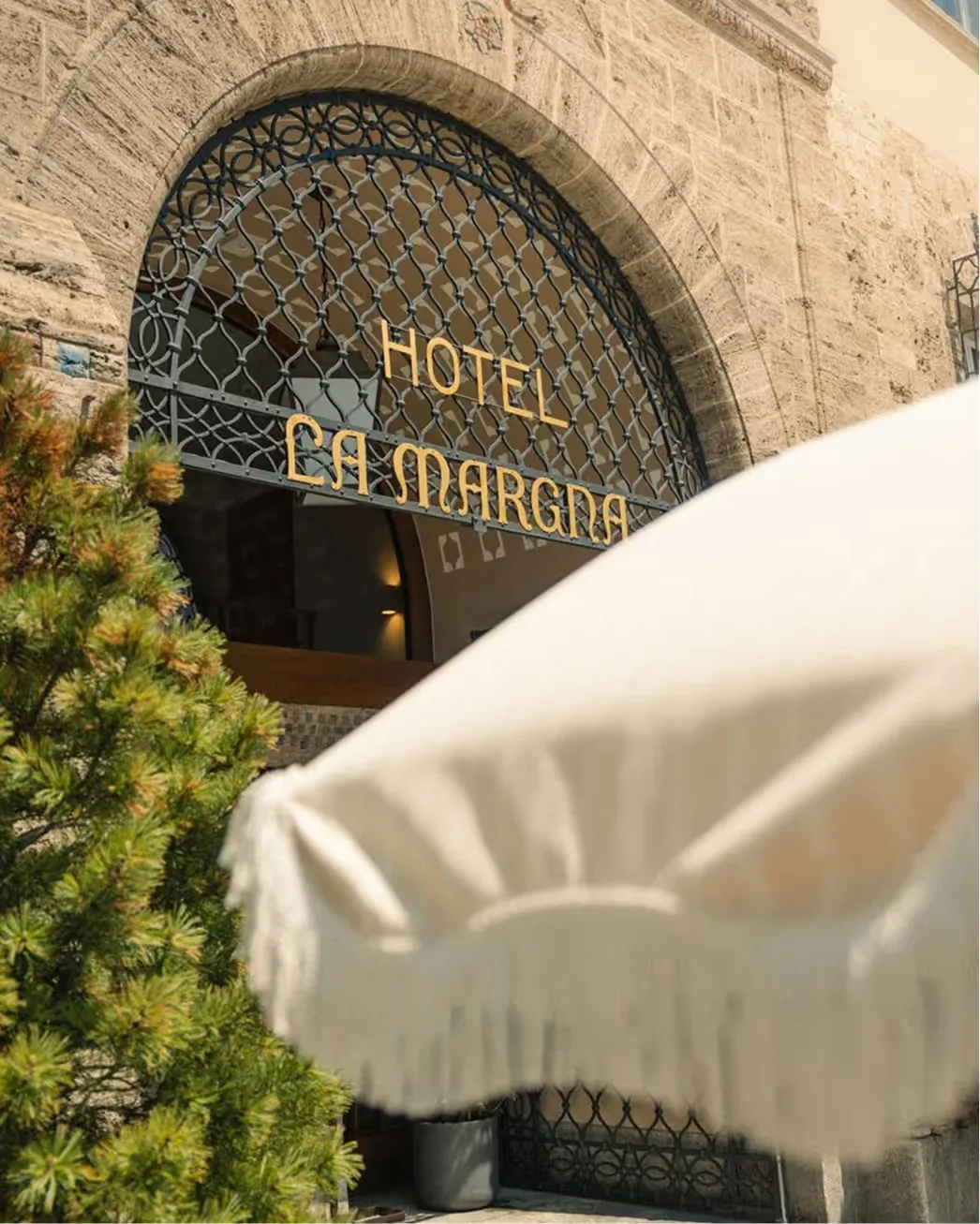 The arched entrance to Grace La Margna with cream-colored parasol in foreground