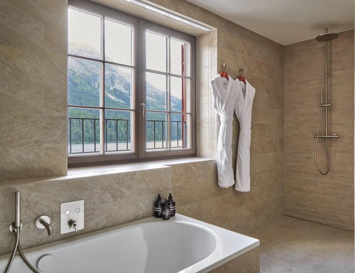 Marble bathroom with stone walls, windows, and modern fixtures against mountain backdrop