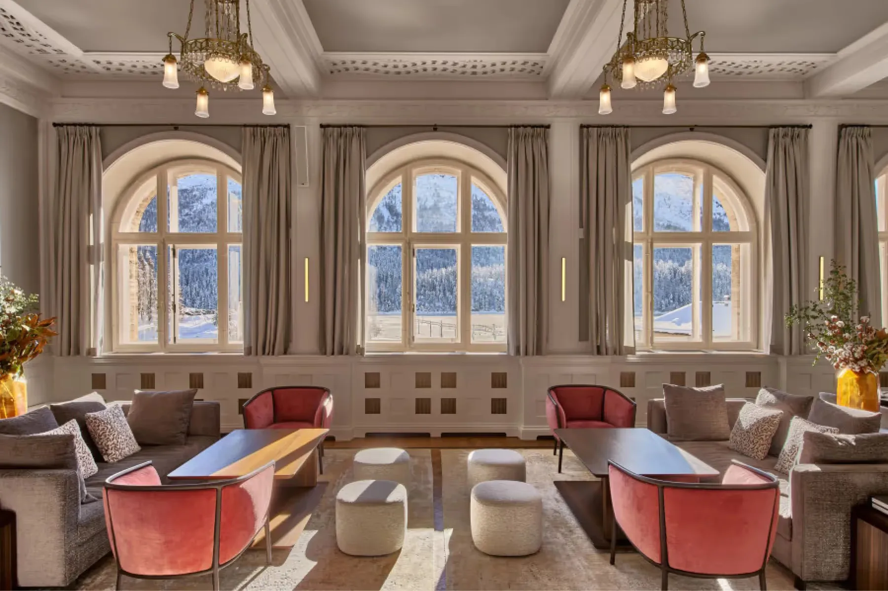 Elegant lounge with arched windows, coral seating, and neutral furnishings in cream tones