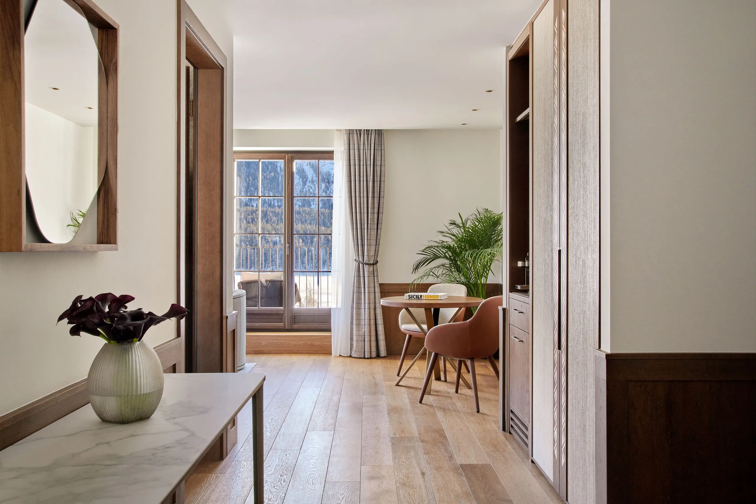 Hallway with white walls, mirror, wood details, and mountain views through open doors