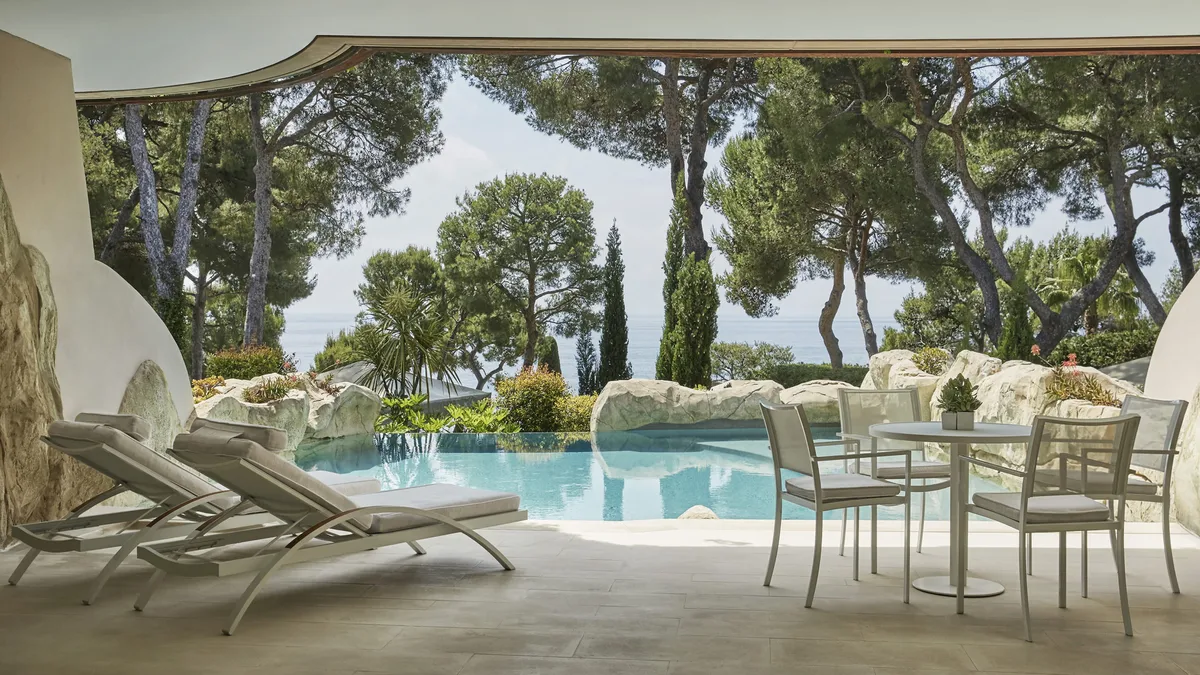 Shaded poolside lounge with Mediterranean plantings and sea horizon