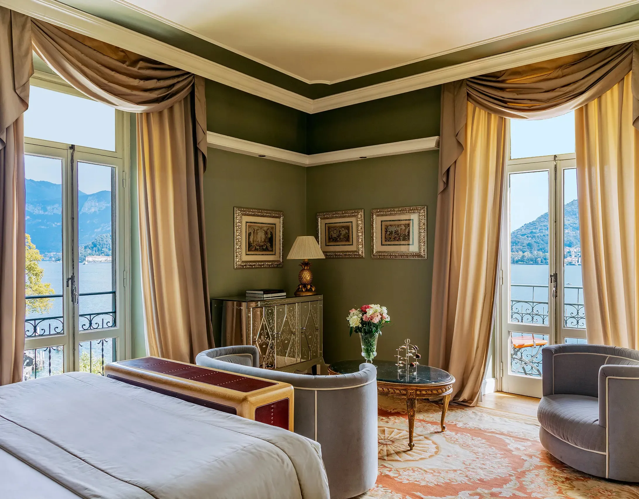 Bedroom with sage-green walls, draped windows, and balcony with distant lake views