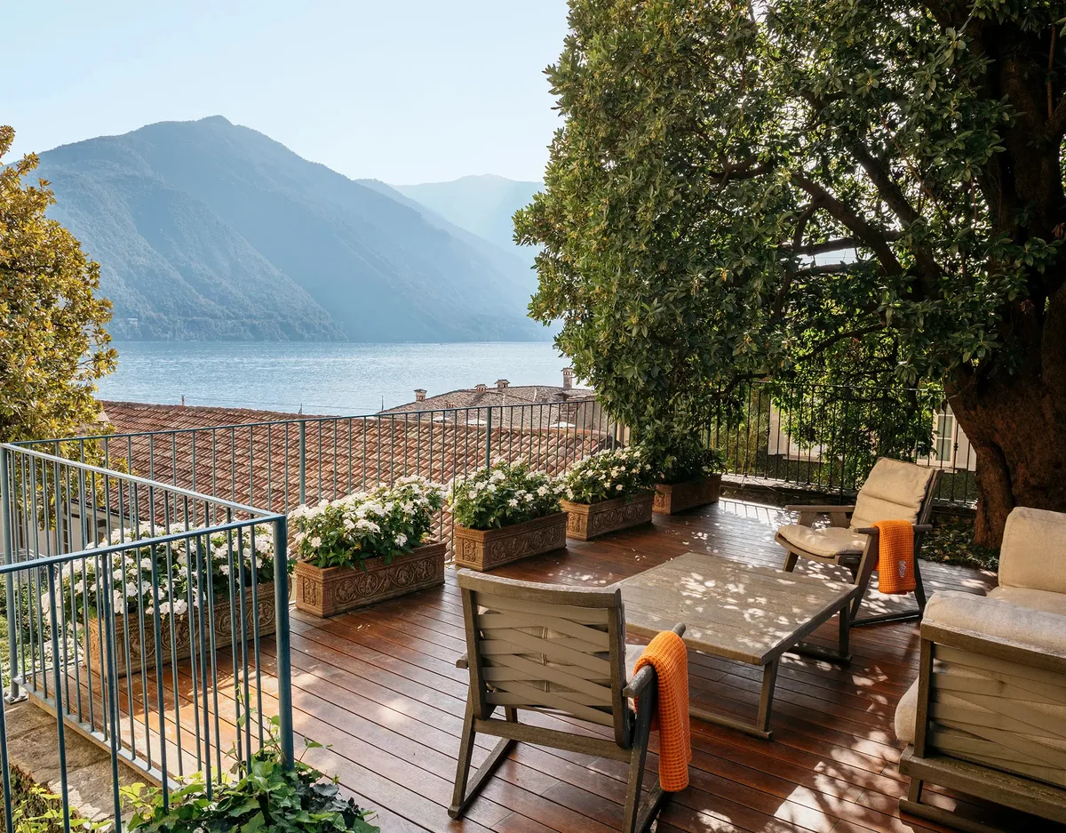 Rooftop terrace with wooden decking, railing, and forested mountain backdrop