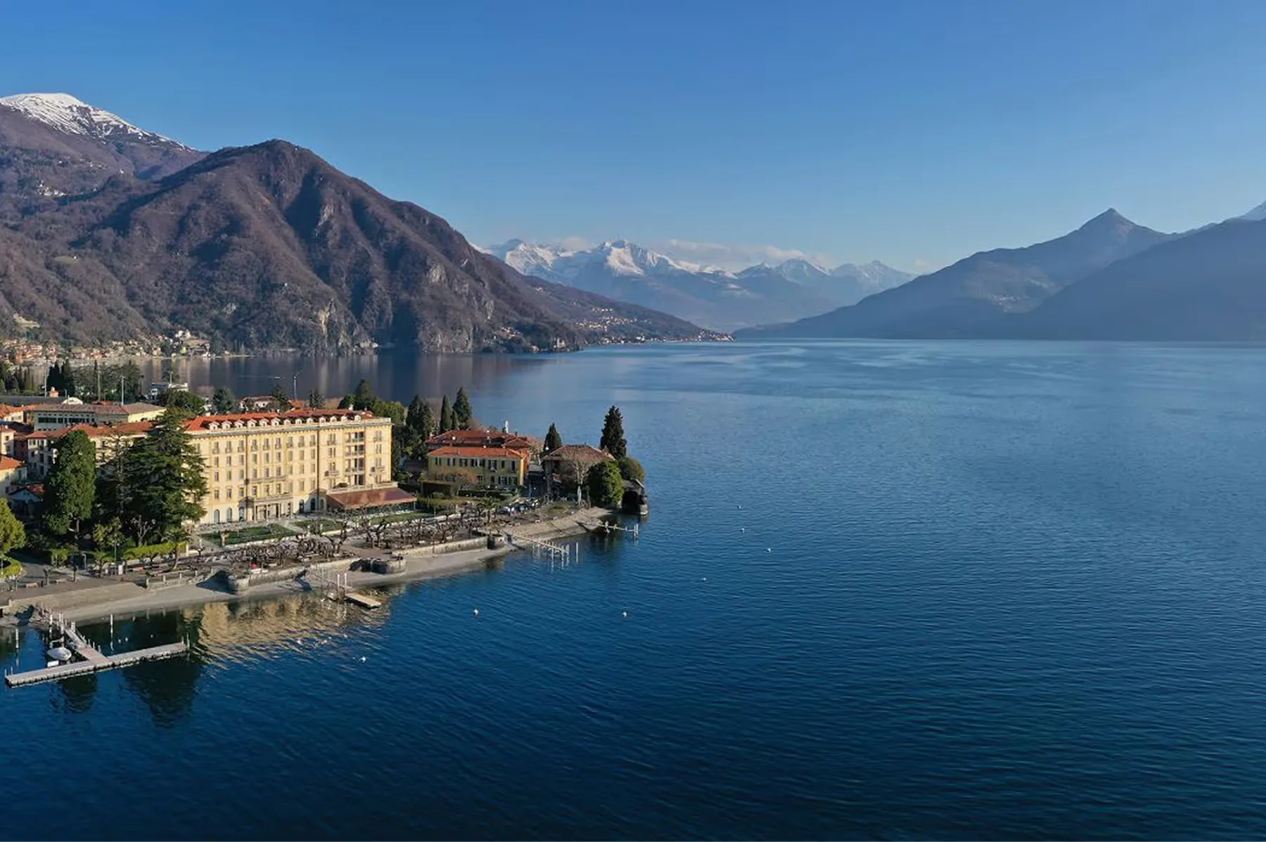 Aerial view of the hotel, pool, and lake with mountains in the distance