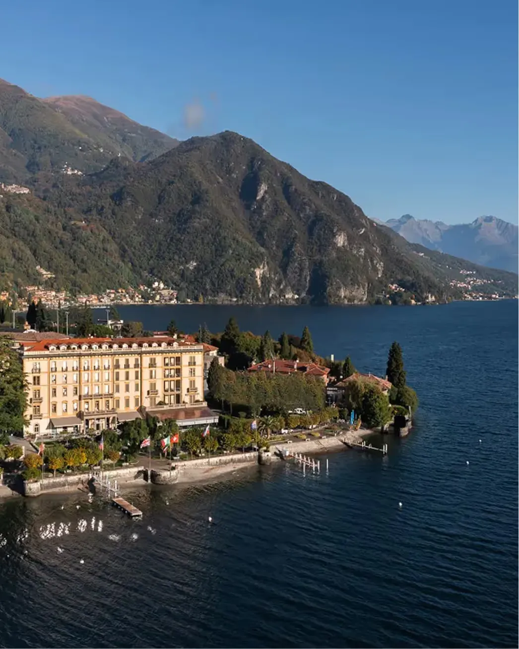 The hotel rises in tiers above the blue lake, with forested mountains beyond