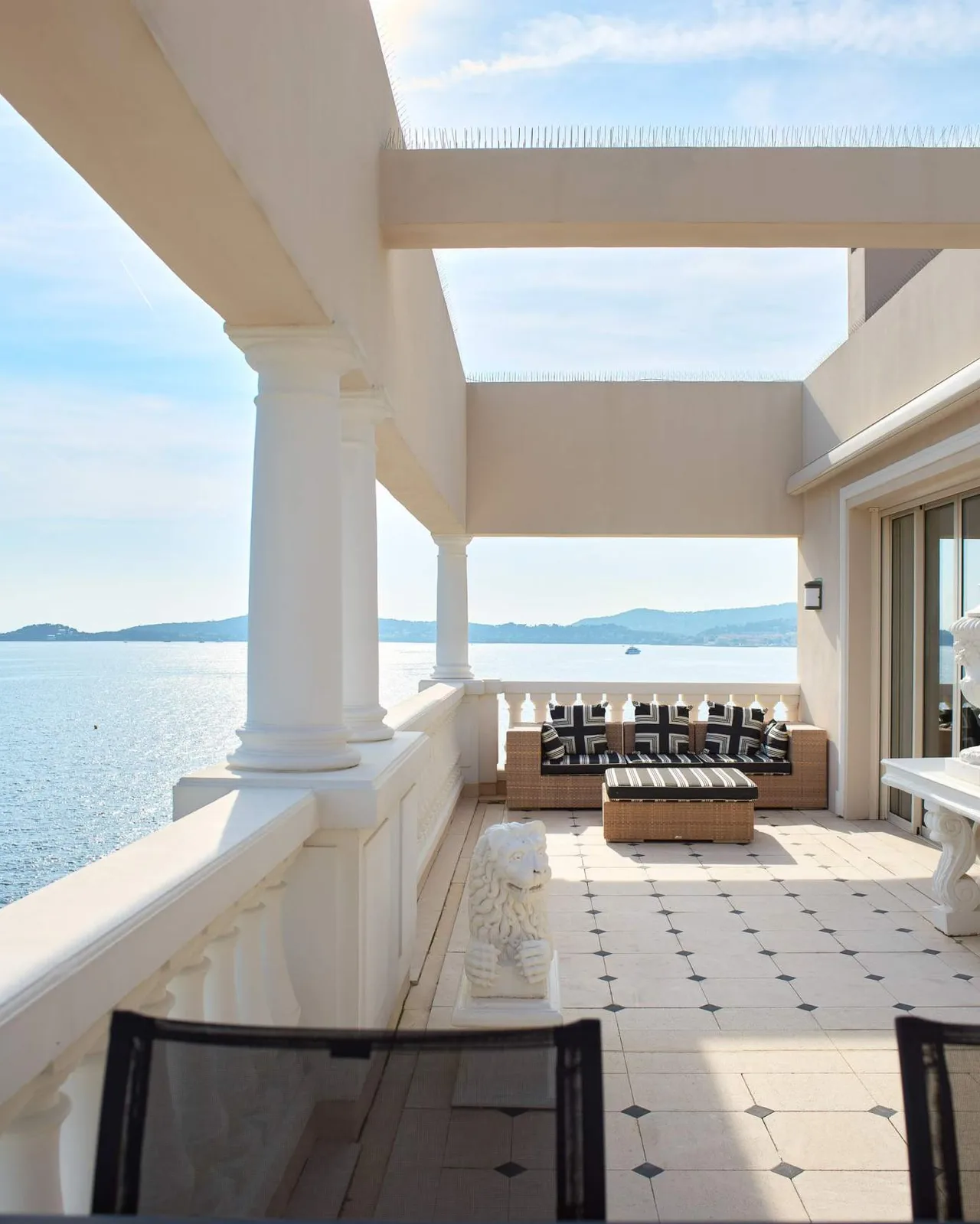 A columned terrace with sea views and lounge seating
