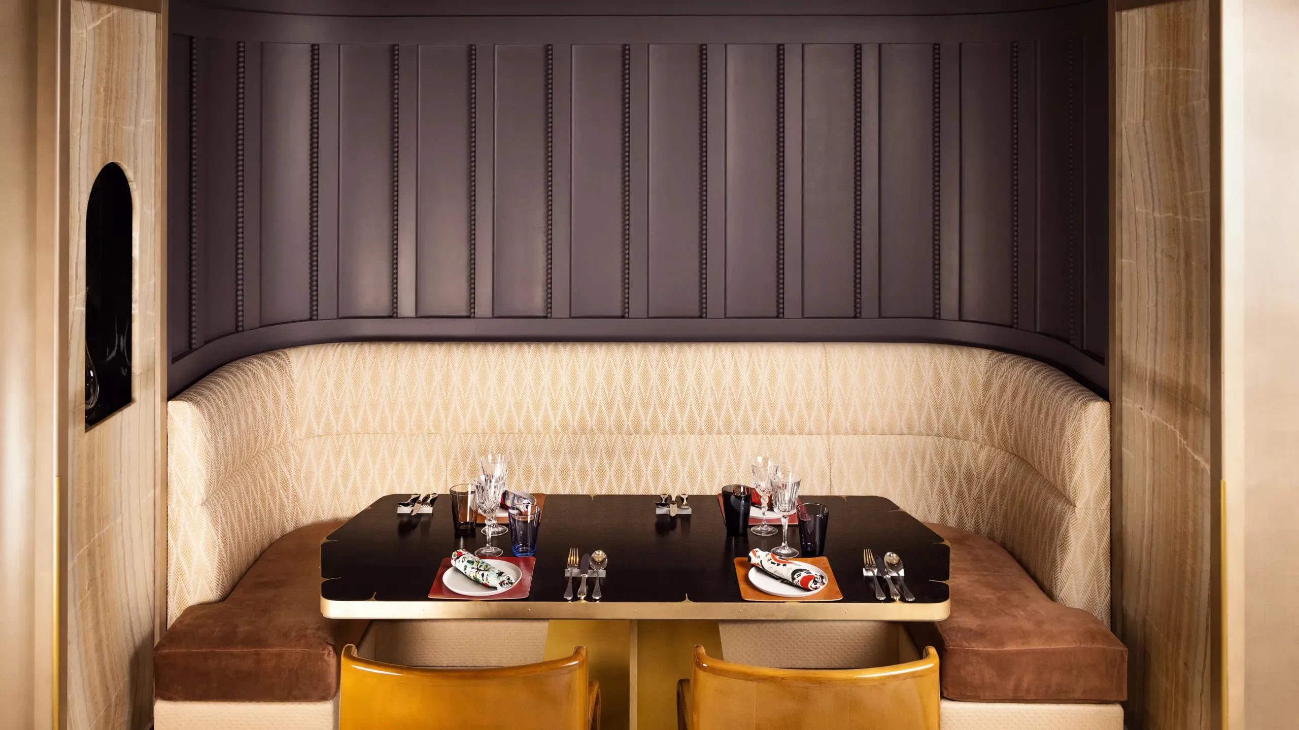 Intimate dining alcove with dark upholstered banquette and copper accents