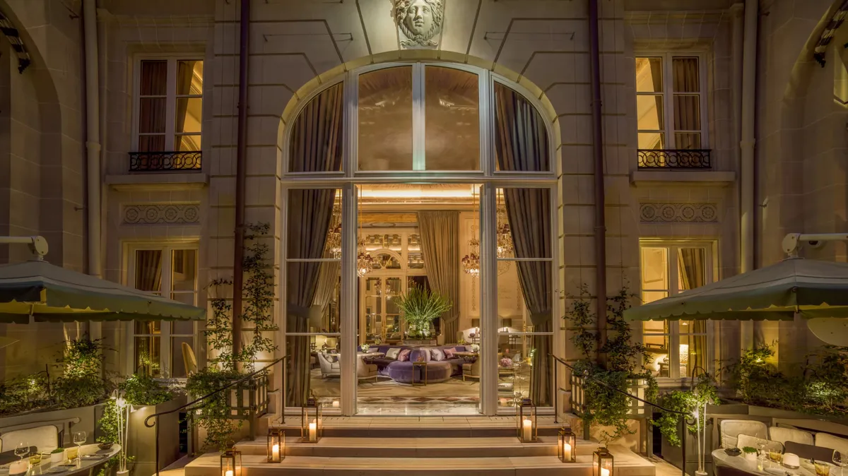 Evening view of arched stone entrance with ornate railings and warm lighting