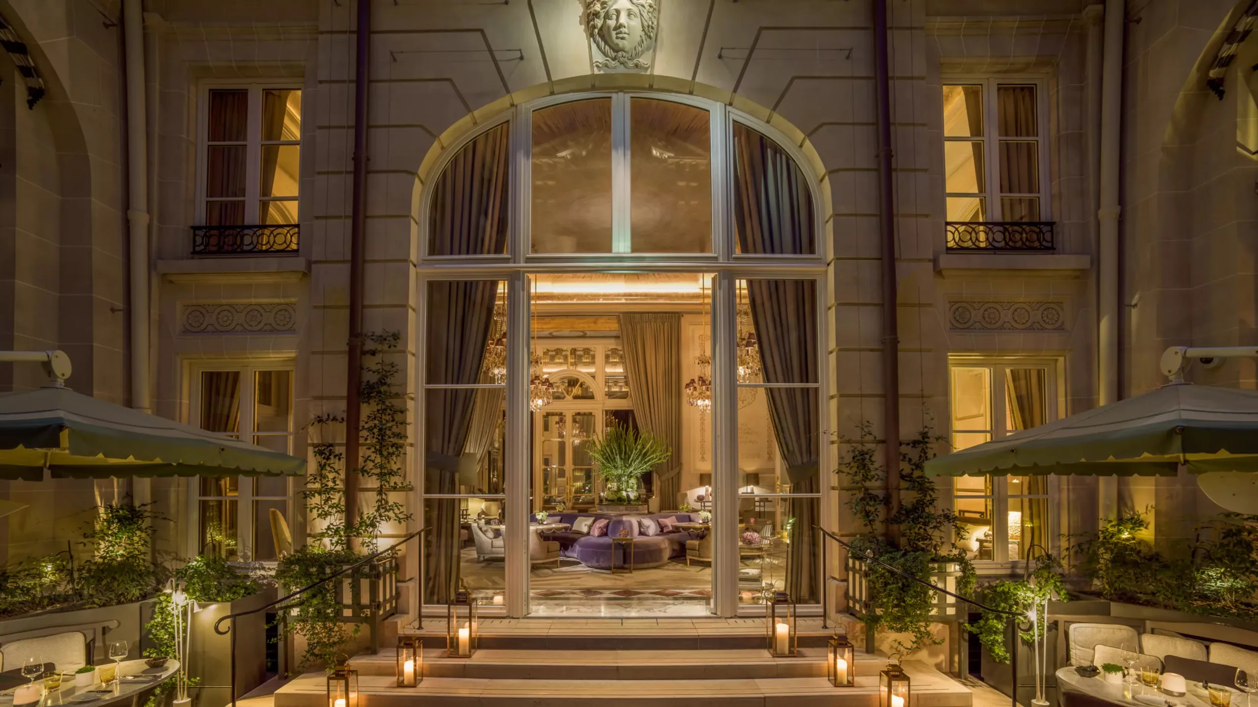 Evening view of arched stone entrance with ornate railings and warm lighting
