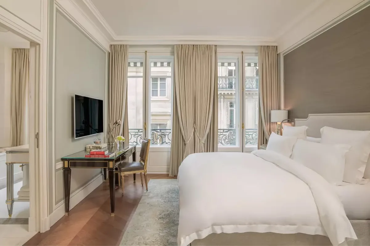 Bright room with white bed, beige walls, tall windows, and hardwood floors